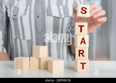 Main de femme mettre cube bois avec bloc de texte START UP sur table. Concept de démarrage Banque D'Images