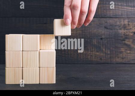 Woman's hand mettant la dernière pièce du cube de bois en place - réalisation concept. Terminer le concept du projet Banque D'Images