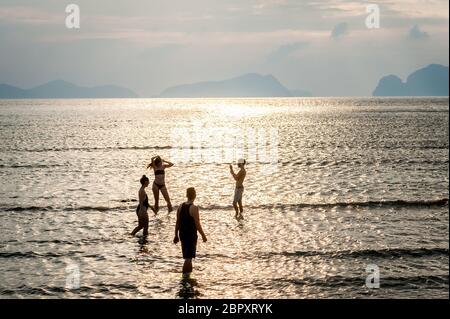 Les couples se sont enroulés dans l'eau pour admirer et photographier le coucher du soleil à Las Cabanas Beach, El Nido, Palawan, Philippines. Banque D'Images