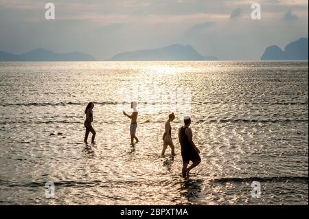 Les couples se sont enroulés dans l'eau pour admirer et photographier le coucher du soleil à Las Cabanas Beach, El Nido, Palawan, Philippines. Banque D'Images