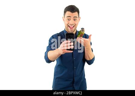 Jeune homme excité posant pour un selfie avec un perroquet peint de parakeet Banque D'Images