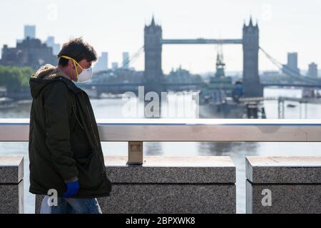 Un homme portant un masque facial de protection traverse le London Bridge, à Londres, pendant l'heure de pointe du matin après l'introduction de mesures pour sortir le pays du confinement. Banque D'Images