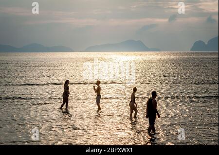 Les couples se sont enroulés dans l'eau pour admirer et photographier le coucher du soleil à Las Cabanas Beach, El Nido, Palawan, Philippines. Banque D'Images