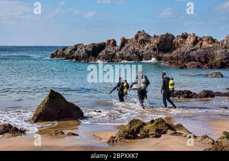 Trois plongeurs entrent en mer dans un petit port de Lanzarote, îles Canaries, Espagne Banque D'Images
