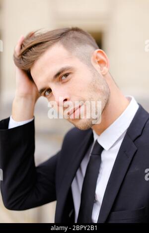 Gros plan d'un jeune homme portant un costume et une cravate de balck. Banque D'Images