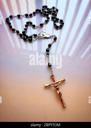 Gros plan vertical d'un collier en croix avec des perles noires sur la table sous les lumières Banque D'Images