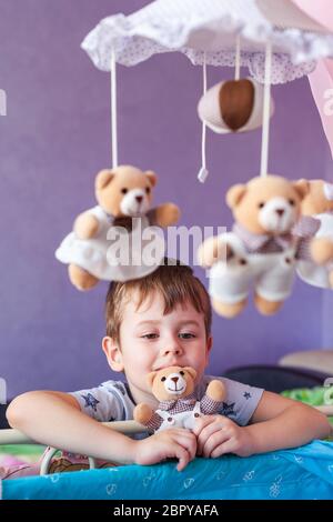Enfant Tenant Un Jouet Little Teddy Bear Adorable Petit Garcon Debout Pres D Un Lit Bebe Avec Carrousel Mobile De Musique De Bebe Photo Stock Alamy