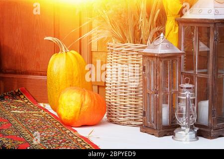 Feuilles jaunes d'automne, citrouilles, automne, paille, porte en bois sur le fond. Composition de jardin, arrosoir vieilli en zinc et chandelier. Banque D'Images