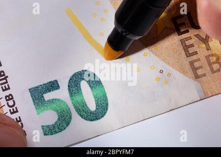 Close-up of Hand écrit le billet suspect avec repère jaune Banque D'Images