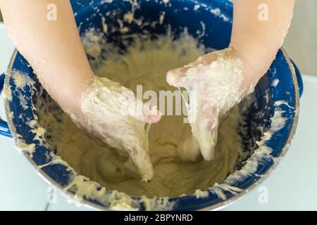 l'enfant pétrir la pâte dans un moule bleu, les mains se ferment. Banque D'Images