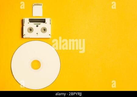 Disque compact et carte mémoire sur fond jaune. Cassette vidéo numérique. Espace de copie Banque D'Images