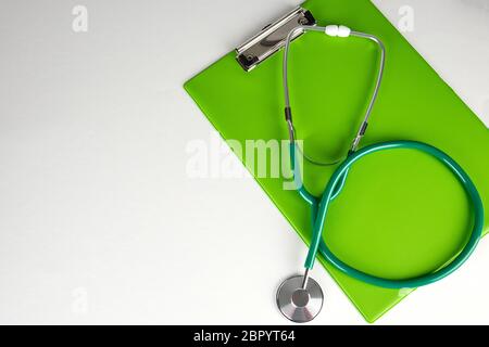 Stéthoscope médical et porte-papier vert sur fond blanc, copy space Banque D'Images