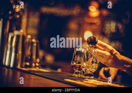 Gros plan d'un bartender pouring dans un verre de whisky Glencairn. Banque D'Images