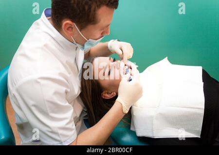 Le dentiste applique du gel de blanchiment sur les dents du patient Banque D'Images