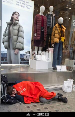 Le mendiant des sans-abri s'est rapidement endormi dans son sac de couchage rouge sur Oxford Street. Londres. Angleterre.Royaume-Uni. Banque D'Images