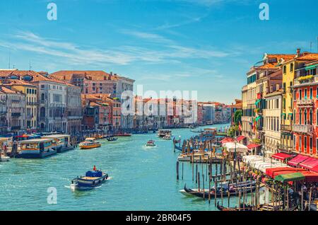 Paysage urbain de Venise avec voie navigable du Grand Canal. Vue depuis le pont du Rialto. Gondoles, bateaux, vaporettos amarrés et bateau à voile Canal Grande. Architecture vénitienne bâtiments colorés. Vénétie, Italie. Banque D'Images