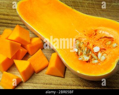 Demi-courge musquée avec des graines sur une planche à découper en bois avec des morceaux de courge musquée de taille peu importante Banque D'Images