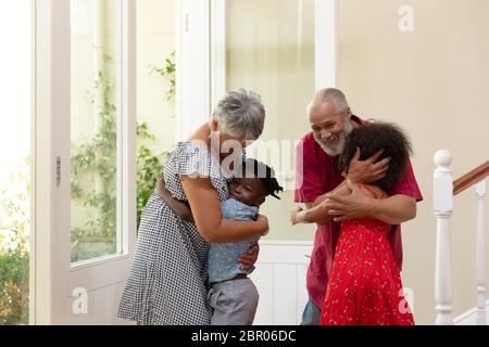 Couple senior de race mixte qui embrasse leur petit-fils et petite-fille Banque D'Images