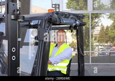 Conducteur de chariot élévateur à tête en cabine avec porte Couverture de pluie Banque D'Images