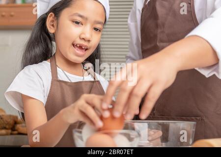 La mère et la fille aident à recueillir des œufs dans des tasses claires placées sur la table pour cuisiner. Sélectionner la profondeur de champ faible focale de mise au point. Banque D'Images