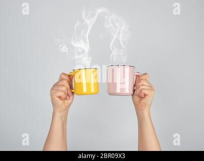 Deux mains levées avec tasses en céramique, d'épaisseur de la vapeur qui sort de la tasse et se connecte, love concept Banque D'Images