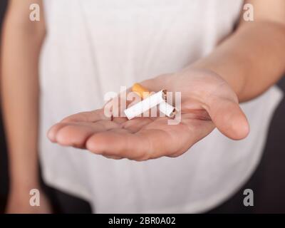 cigarette cassée dans une main féminine, cesser de fumer, dépendance à la nicotine. Banque D'Images