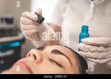 Le médecin esthéticienne applique de l'huile à la peau du visage Banque D'Images