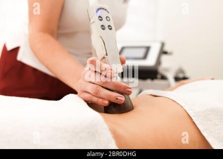 Le médecin cosmétologue fait un massage anti-cellulite à l'aide d'un dispositif à vide Banque D'Images
