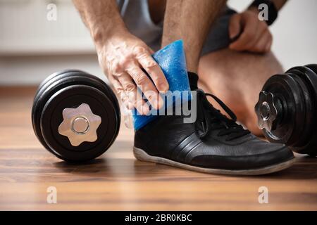 La section basse d'un homme l'application de glace de gel au sur une cheville blessée dans une salle de sport Banque D'Images