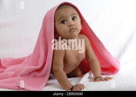 Mumbai, Maharashtra, Inde, Asie, 16 septembre 2007 - Portrait d'indien petit bébé mignon souriant jouant enveloppé dans une serviette rose sur fond blanc Banque D'Images