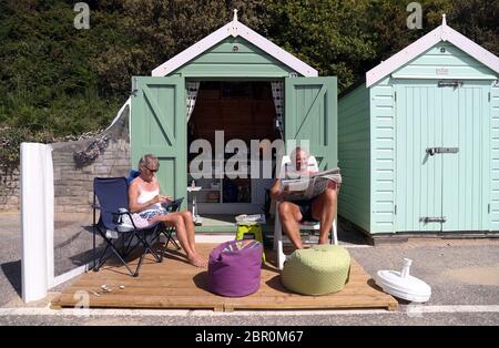 Rob et Sally Underhill s'assoient à l'extérieur de leur cabane de plage pendant qu'ils apprécient le temps chaud à la plage de Bournemouth à Dorset, tandis que les gens affluent vers les parcs et les plages avec des mesures de verrouillage assouplies. Banque D'Images