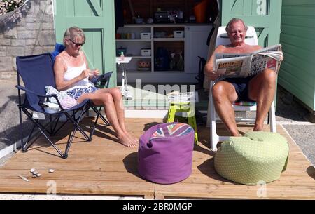 Rob et Sally Underhill s'assoient à l'extérieur de leur cabane de plage pendant qu'ils apprécient le temps chaud à la plage de Bournemouth à Dorset, tandis que les gens affluent vers les parcs et les plages avec des mesures de verrouillage assouplies. Banque D'Images