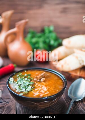 Cuisine géorgienne traditionnelle-soupe Kharcho avec viande, riz et coriandre fraîche.soupe Spicy Kharcho sur table en bois avec pain traditionnel Shotis Puri, vint Banque D'Images