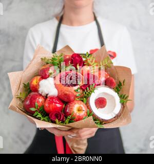 Bouquet de fruits et de baies. Bouquet de l'alimentation de femmes. Grenade, fraise, pommes, noix de coco et fleurs roses, d'eucalyptus. Shallow DOF Banque D'Images