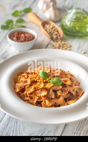 Partie de farfalle avec pesto aux tomates séchées avec des ingrédients sur la table en bois blanc Banque D'Images