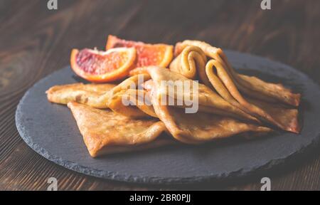 Crêpes Suzette avec des tranches d'orange sanguine sur le conseil de pierre noire Banque D'Images