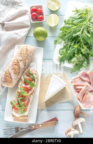 Sandwich avec du fromage à la crème, poulet fumé, tomates cerises et de la roquette Banque D'Images