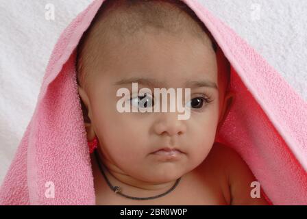 Mumbai, Maharashtra, Inde, Asie, 16 septembre 2007 - Portrait d'indien 6 mois petit bébé mignon sourire jouant enveloppé d'une serviette rose sur le dos blanc Banque D'Images