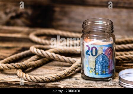 Composition sur fond de bois avec des billets d'argent économisant dans un pot en verre. Concept d'investissement et de maintien de l'argent, isolé. Banque D'Images