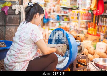 La chair d'une noix de coco étant enlevée de la coquille à un marché. Siem Reap, Cambodge, Asie du Sud-est Banque D'Images