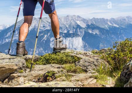 Gros plan de jambes mâles musclés et veiny avec bâtons de randonnée pour la marche nordique sur fond de la chaîne de montagnes alpines dans la vallée de Ziller, Banque D'Images