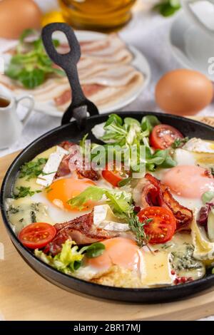 Oeufs au plat avec du bacon croustillant et petit camembert dans une poêle pour le petit déjeuner Banque D'Images