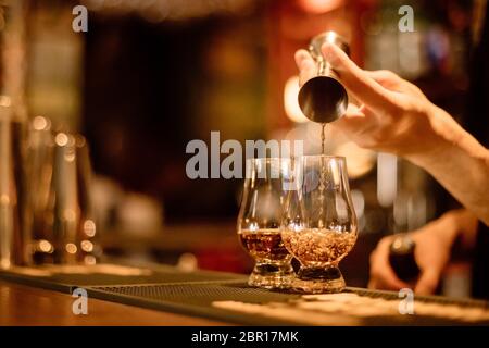 Gros plan d'un bartender pouring dans un verre de whisky Glencairn. Banque D'Images