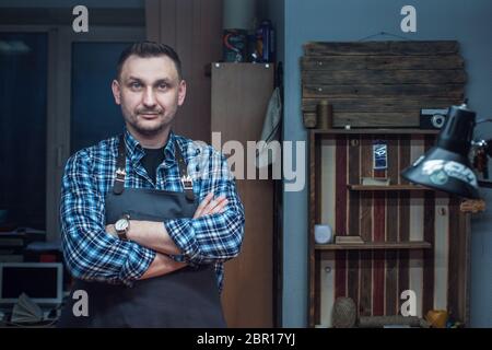 Travail avec le cuir homme lors d'un atelier textile. Portrait masculin. Concept de la production artisanale à la main des articles en cuir. Banque D'Images