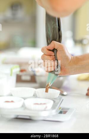 Femme chef pâtissière professionnel pâte à tartiner la pâte au chocolat dans le plat de cuisson. Banque D'Images