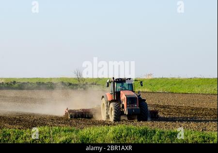 Un tracteur avec une charrue fixe le sol. La culture du sol sur le terrain pour le semis. Banque D'Images