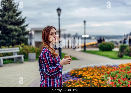 Café sur le rendez-vous. Belle jeune femme holding Coffee cup and smiling in the park Banque D'Images