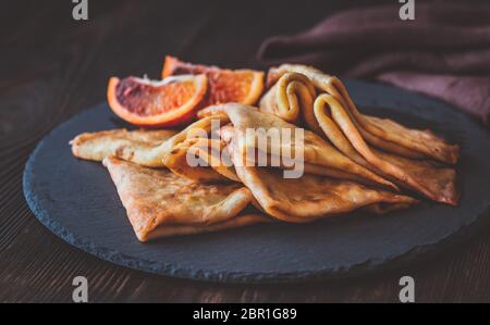 Crêpes Suzette avec des tranches d'orange sanguine sur le conseil de pierre noire Banque D'Images