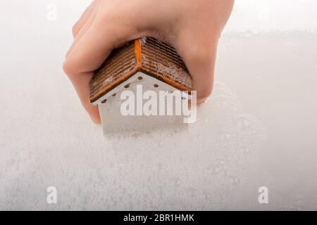 Main tenant une maison modèle dans l'eau mousseuse Banque D'Images