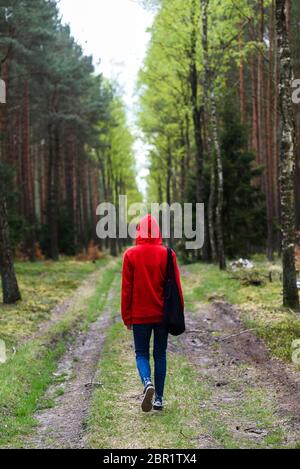 Une femme marchant dans la forêt dans une cagoule rouge. Banque D'Images